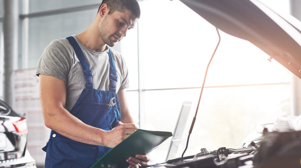 Picture showing muscular car service worker repairing vehicle.